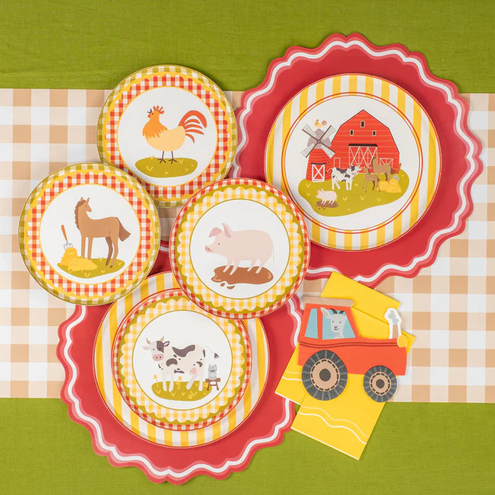Assorted farm animal plates arranged with one tractor napkin to the side.