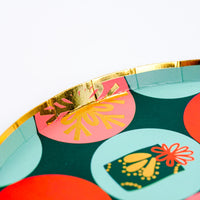 Closeup of dessert plate with gold foil rim and retro holiday dots in red, pink, and mint on dark green.