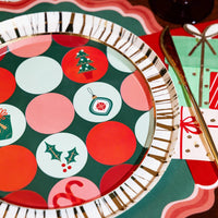 Dot print dessert plate with gold rim layered on scalloped placemats next to a gift shaped napkin.