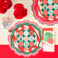 Dot dessert plate on striped charger with scalloped placemats, red florals, and a gift napkin.