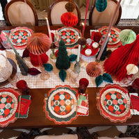 Overhead holiday table with Gatherings plates, scalloped placemats, candles, and honeycomb trees.