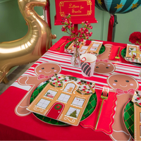Holiday table styled with gingerbread placemats, red striped runner, and festive balloons.