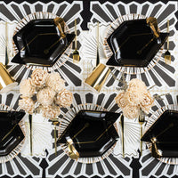 Black and gold tablescape using white napkins with gold rays as the beverage napkins.
