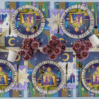 Overhead spread of multiple nativity place settings with white napkins edged in gold.