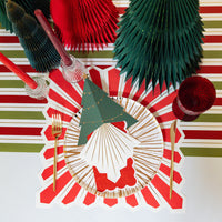Overhead place setting with red and green runner and a white napkin with gold rays.