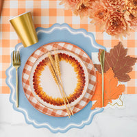 Fall place setting with white guest towel that has a gold zigzag edge layered beside leaf napkins.