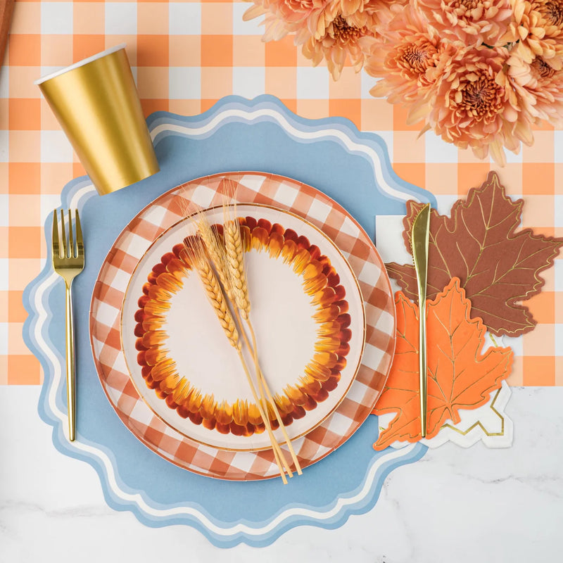 Fall place setting with white guest towel that has a gold zigzag edge layered beside leaf napkins.