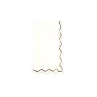 Isolated folded white guest towel with a gold zigzag border on right side.
