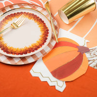 Close view of plates with a pumpkin napkin and a white gold edged guest towel underneath.