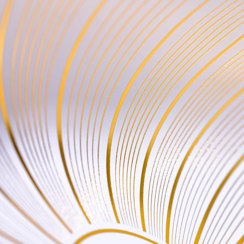 Macro view of gold foil curved lines on a white paper placemat.