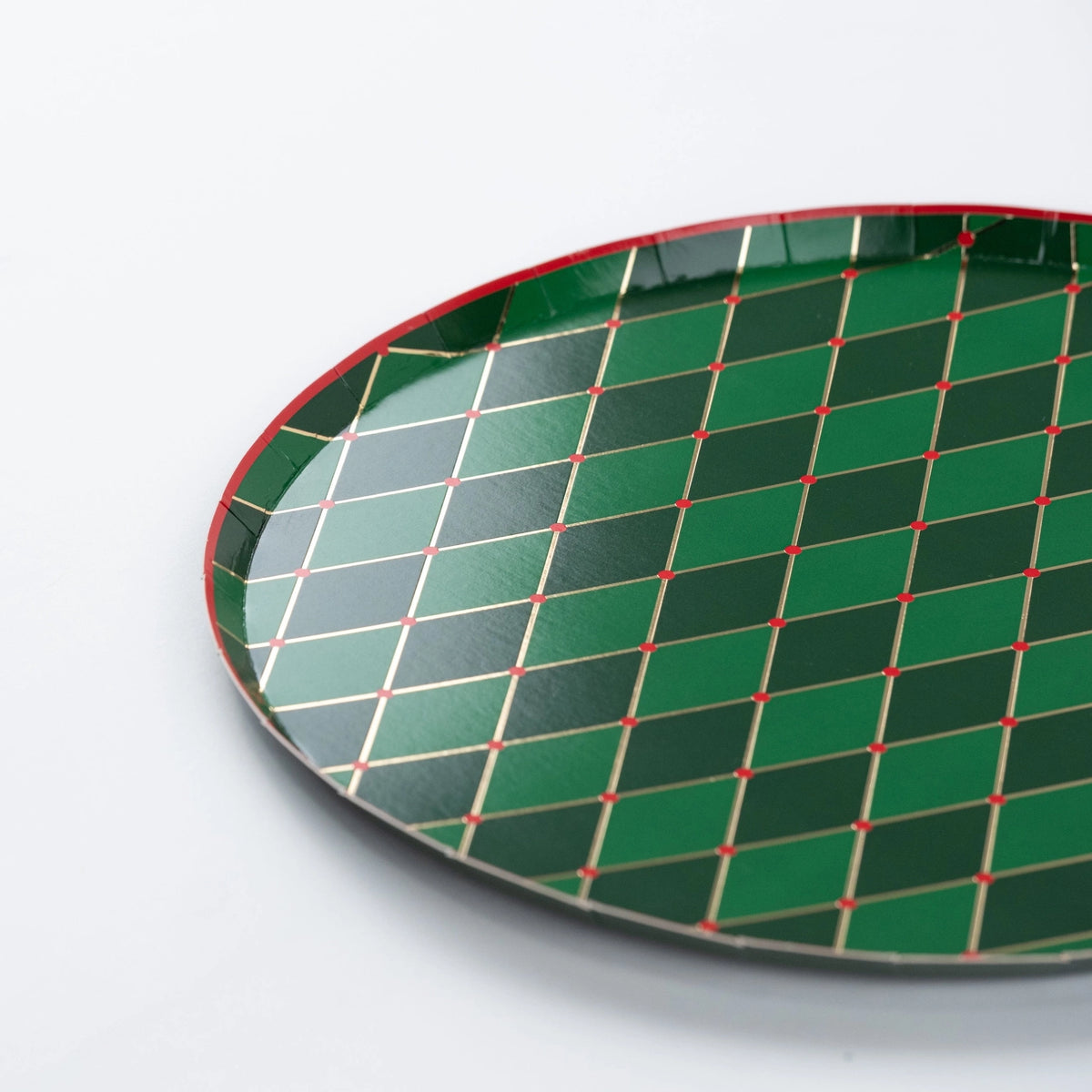 Closeup of green diamond paper dinner plate with gold grid and red rim.