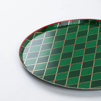 Closeup of green diamond paper dinner plate with gold grid and red rim.