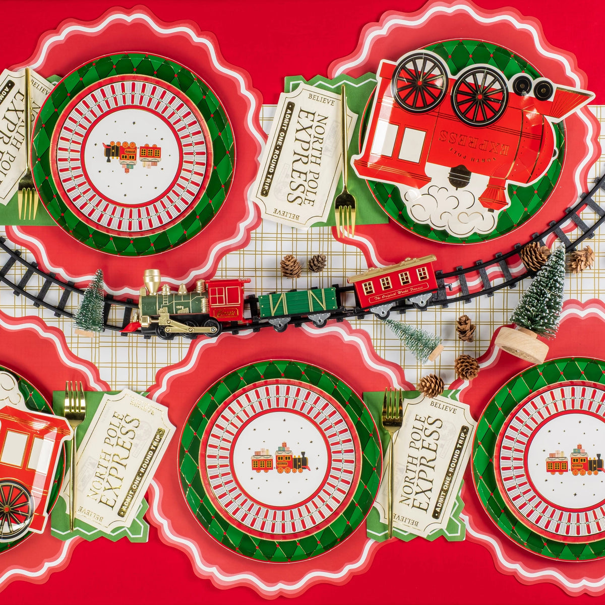 Holiday tablescape with train plates layered over green diamond chargers.
