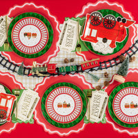 Holiday tablescape with train plates layered over green diamond chargers.