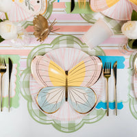 Styled place setting using green gingham scalloped placemat under pastel butterfly plates.