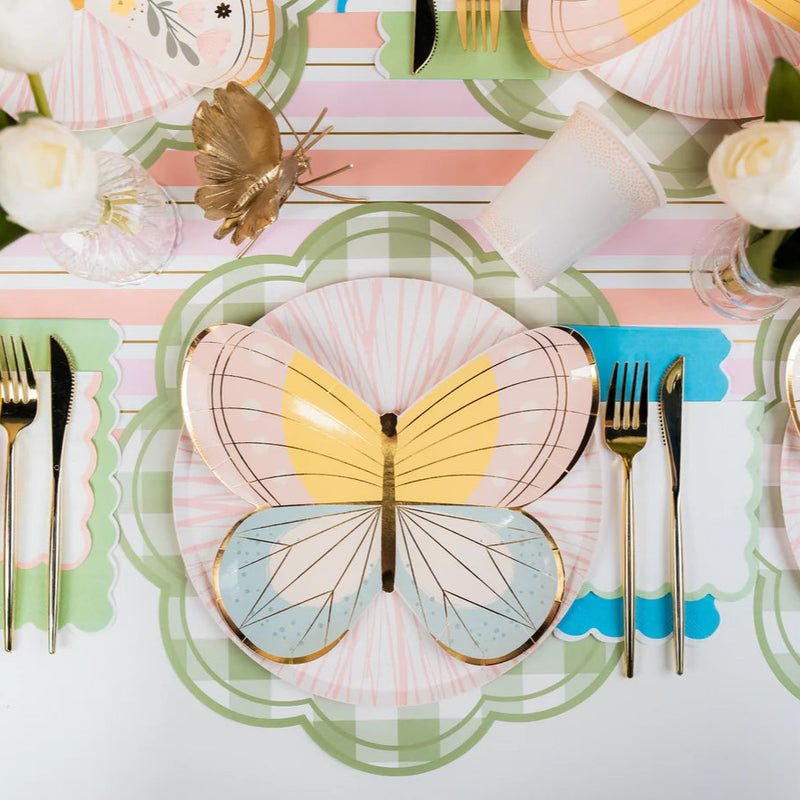 Styled place setting using green gingham scalloped placemat under pastel butterfly plates.