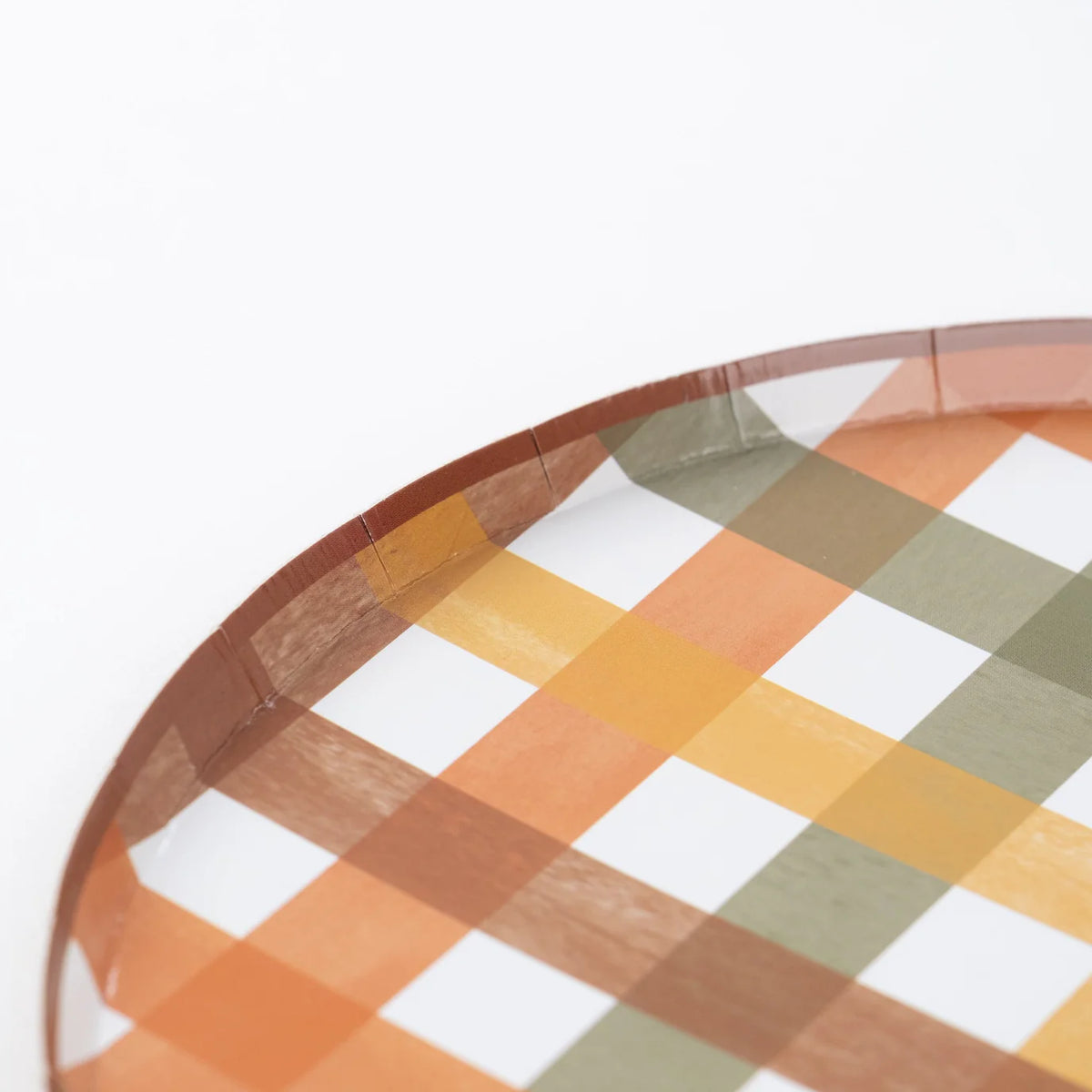 Edge detail of plaid dinner plate with warm fall colors on a white background.