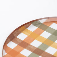Edge detail of plaid dinner plate with warm fall colors on a white background.