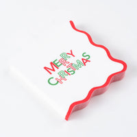 Stack of white cocktail napkins with Merry Christmas text and red wavy edge.