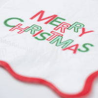 Closeup of red and green Merry Christmas lettering on white napkin.
