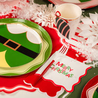 Close place setting with elf plate, ornament cup, and Merry Christmas napkin.