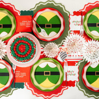 Holiday table with elf plates, red and green decor, and Merry Christmas napkins.