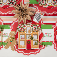 Close overhead of gingerbread table with Merry Christmas napkins and gold flatware.