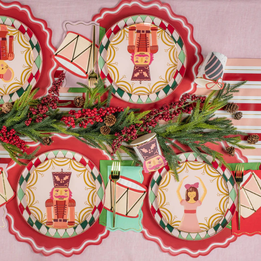 Overhead nutcracker tablescape with plates, drum napkins, and greenery garland.