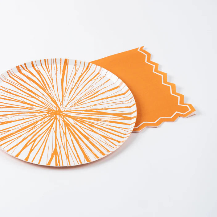 Plate and orange guest towel arranged together on a white background.