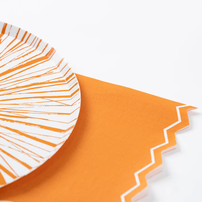 Orange guest towel styled under a white plate with orange splash stripes.