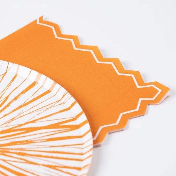 Zigzag edge detail of orange guest towel layered with a patterned plate.