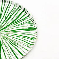 Edge view of green Radiance dinner plate showing burst lines and rim.