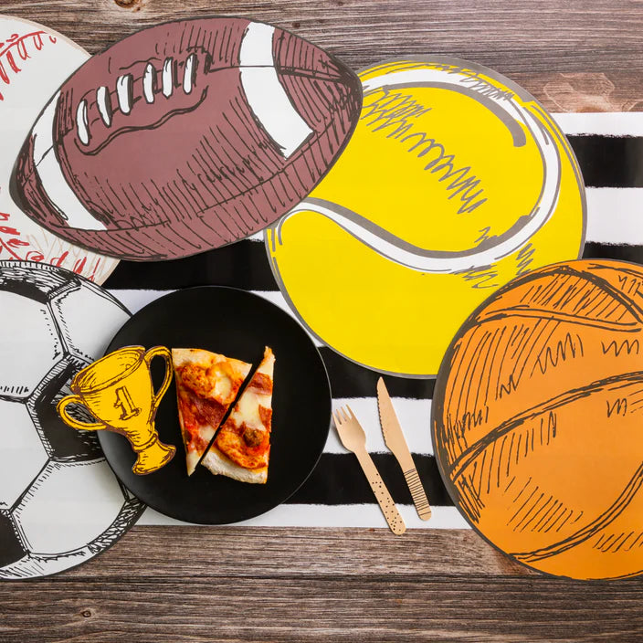 Sports themed table with large tennis, football, soccer, and basketball placemats around a black plate of pizza.