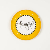 Mustard yellow dessert plate with “thankful” in script and white dots on the rim.