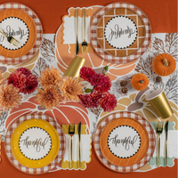 Overhead fall tablescape with mixed “thankful” dessert plates, mums, pumpkins, and gold cups.