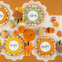 Overhead table showing multiple place settings with assorted “thankful” dessert plates.