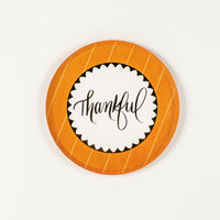 Pumpkin orange striped dessert plate with “thankful” center on white background.
