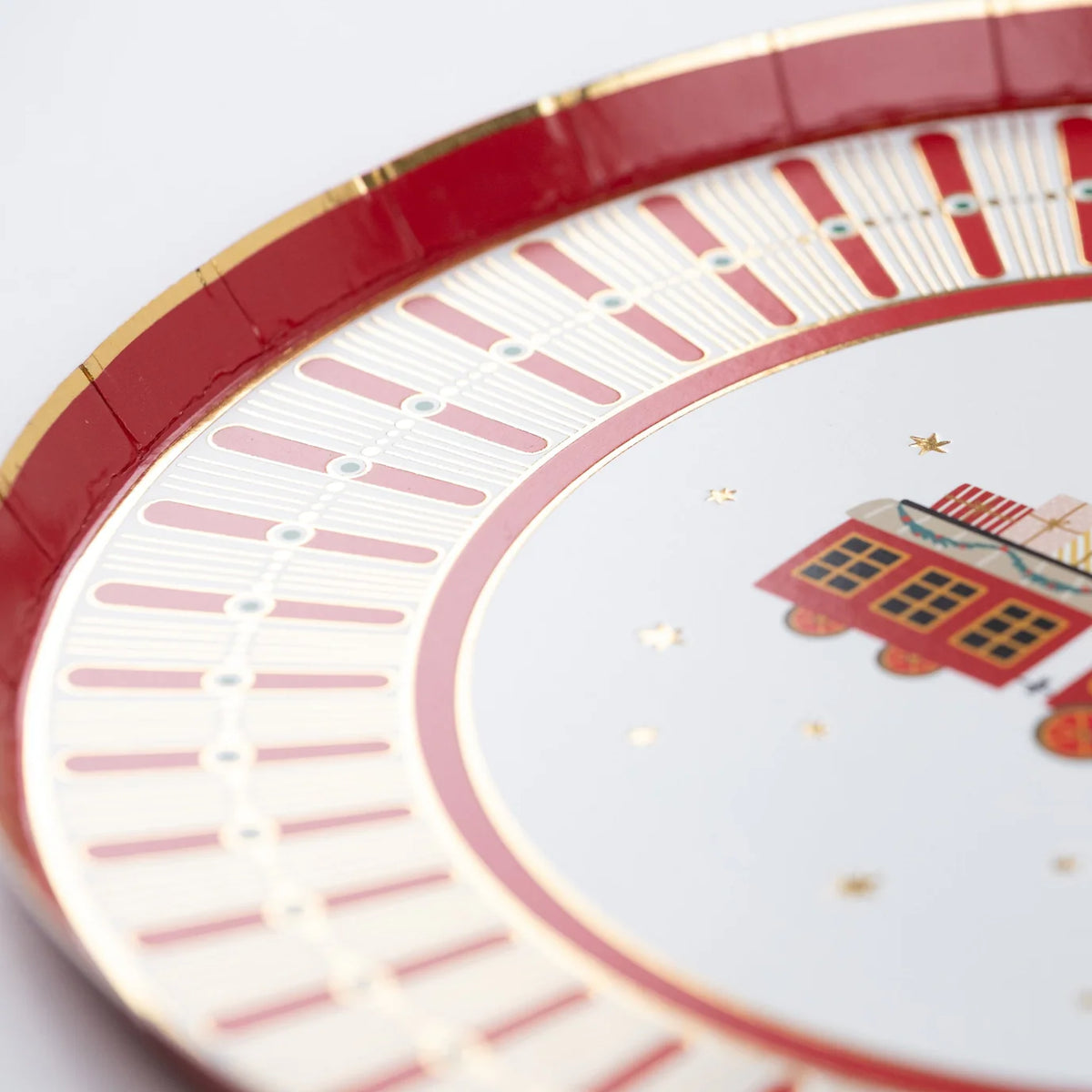 Angle view of plate rim showing red and gold details around the train design.