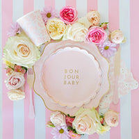 Flat‑lay tablescape featuring Bonjour Baby plates, matching napkins and cups for French‑inspired baby shower.