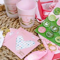 Flat-lay of Camp Bachelorette flex cups surrounded by keychains, pins, and party favors