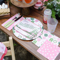 Outdoor bachelorette table with drinks, flowers, and Camp Bachelorette large napkins under plates