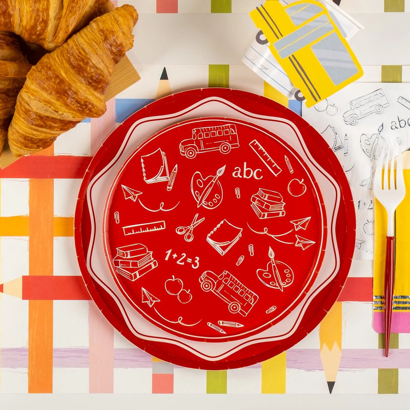 Red back-to-school plate on pencil-stripe placemat beside school-bus cup and napkin.