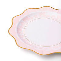 Mixed tableau of pink and blue floral plates for gender‑reveal garden tea.