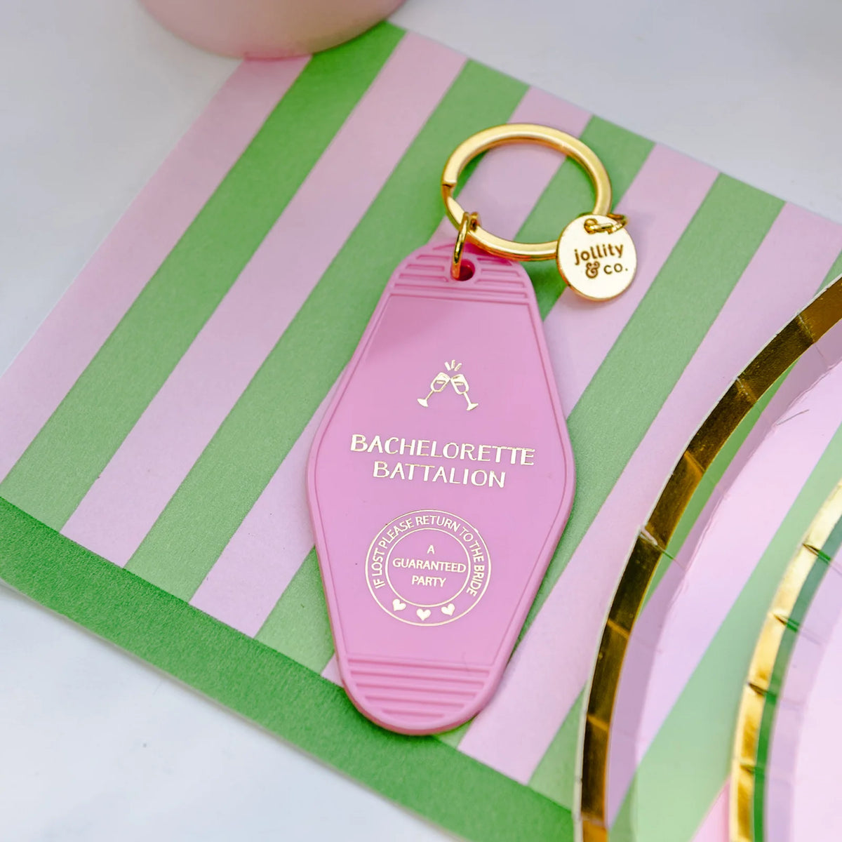 Close-up of pink and green striped napkin topped with “Bachelorette Battalion” motel key tag