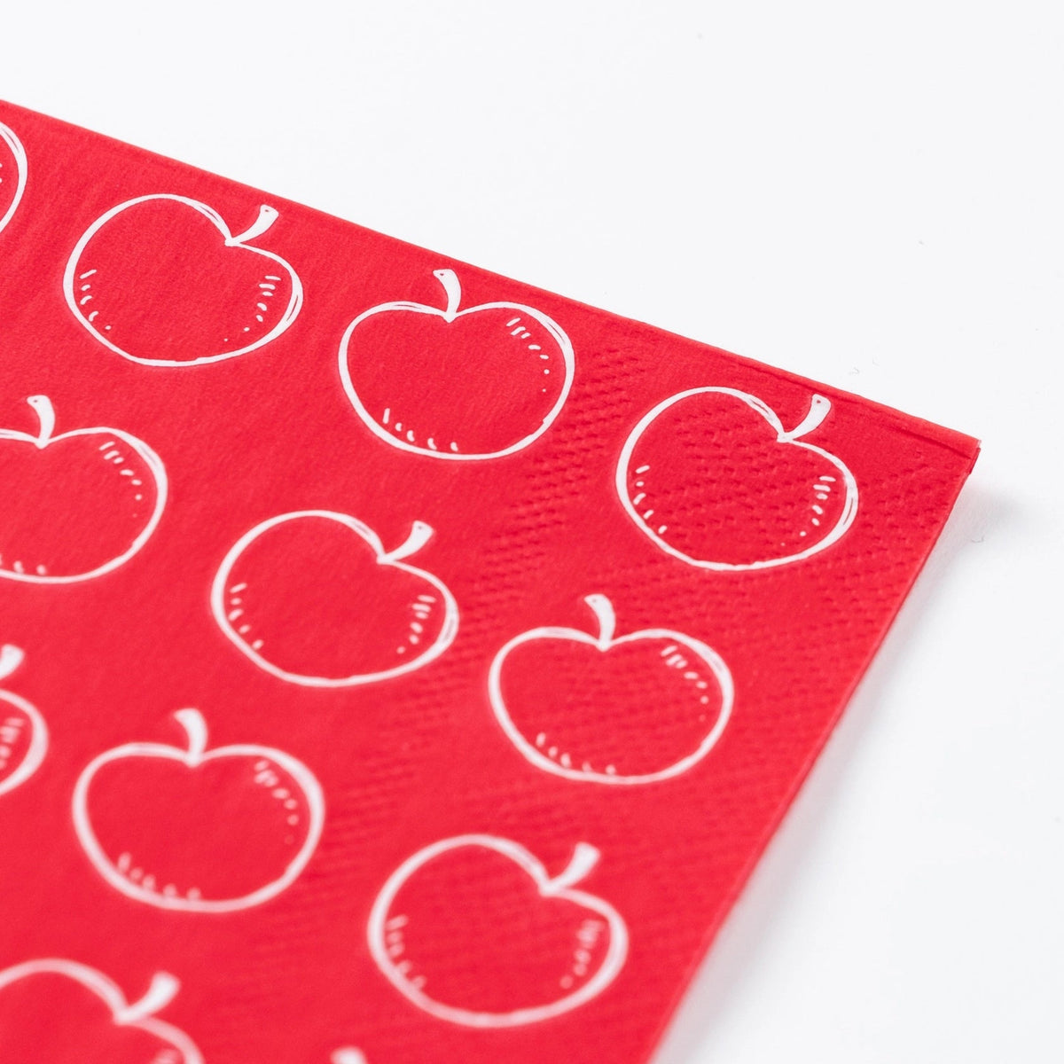 Angled view of full apple guest towel laid flat on white surface.