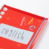 Close-up of red notebook-shaped plate labeled ‘English’ with spiral detail.