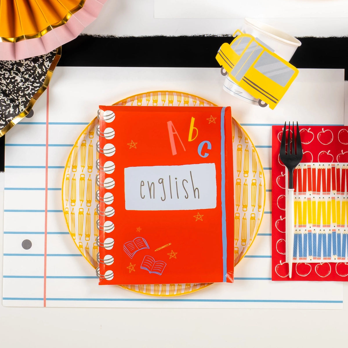 English notebook plate displayed on pencil plate with apple guest towel and school bus cup.