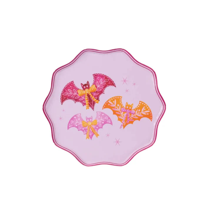 Product shot of one pink scalloped dinner plate with three bats and bows on a white background.