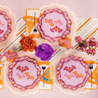 Overhead tablescape with multiple pink dinner plates, matching cups, and florals from the Bats and Bows collection.