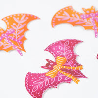 Assorted pink and orange bat stickers scattered on a white background from the Bats and Bows set.
